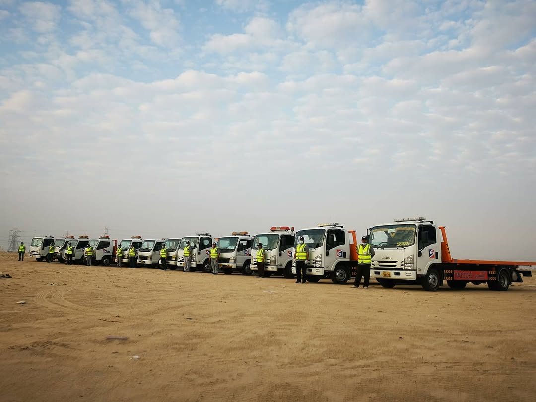 Al Sham Isuzu fleet lineup with crew in hi-vis vests in Kuwait desert